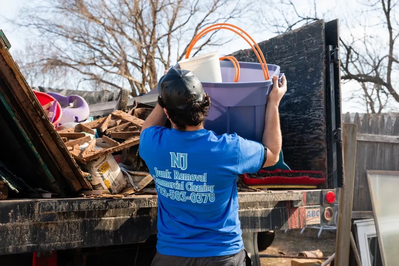 A crew member loading household clutter onto the back of the truck