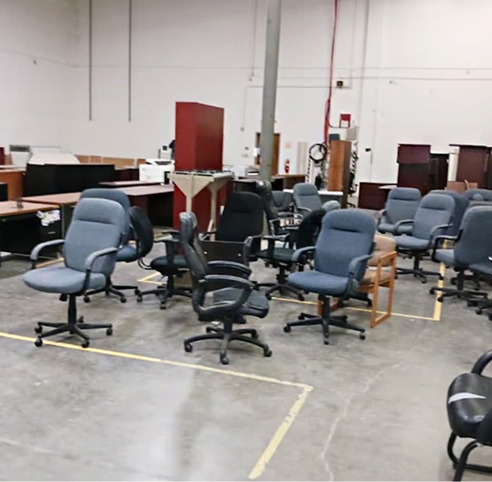 A warehouse filled with surplus office chairs and desks awaiting commercial junk removal