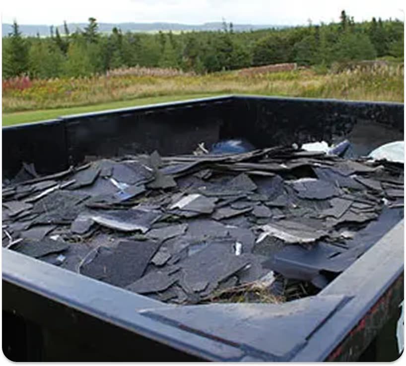 A roll-off dumpster filled level with stripped roofing shingles